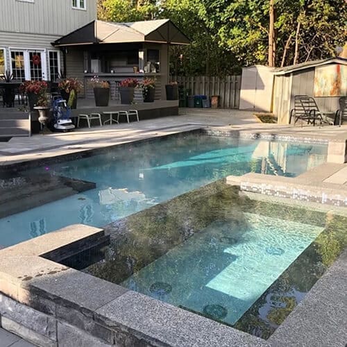 Stone Haven Developments Modern backyard by Stone Haven Developments featuring a rectangular swimming pool and built-in hot tub, surrounded by elegant stone paving; comfortable seating and lush greenery create a tranquil retreat in the background. Ontario