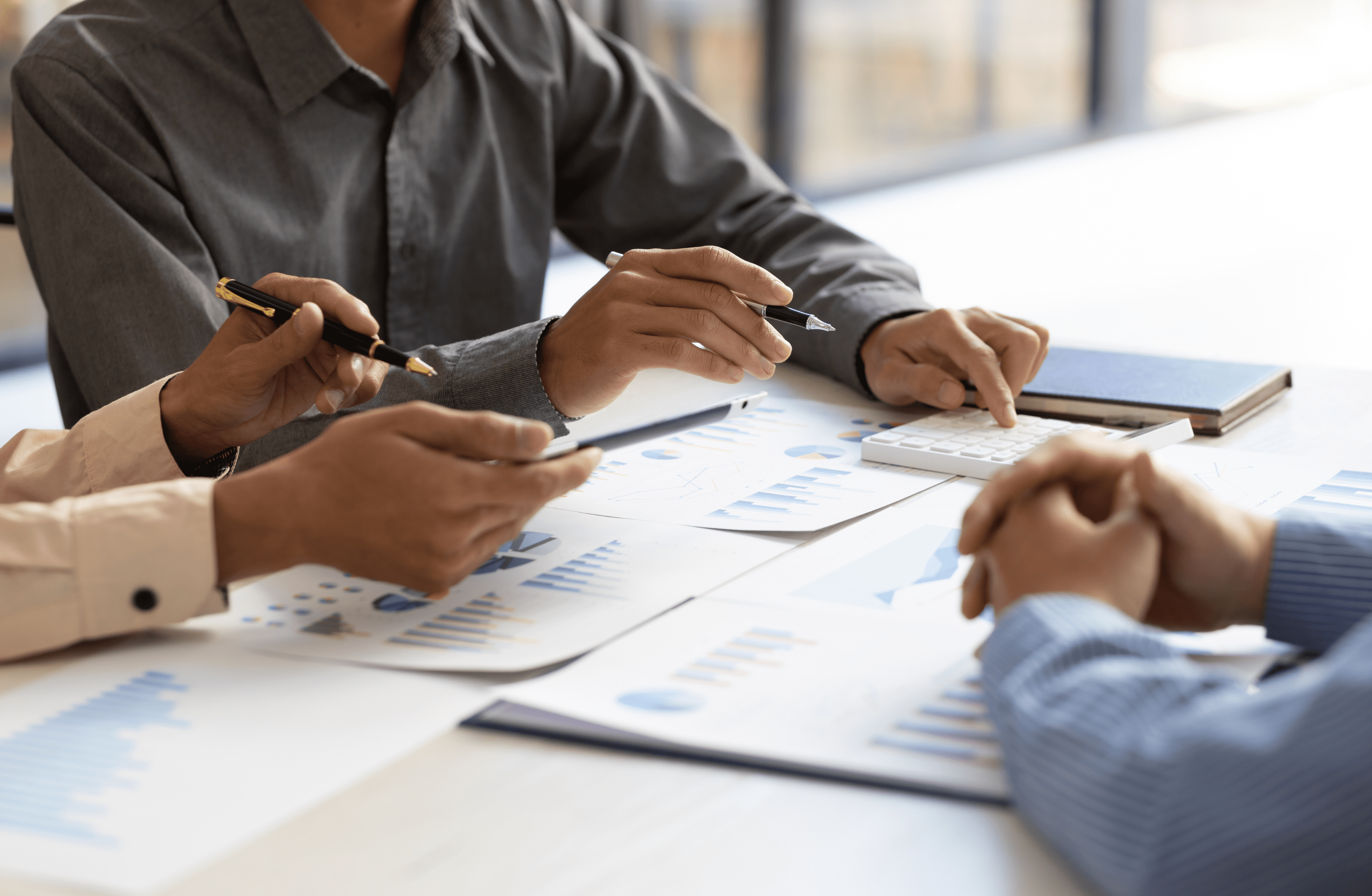 Stone Haven Developments Three people at a table review financial charts and data for Stone Haven Developments, using pens, a calculator, and documents with graphs. Ontario