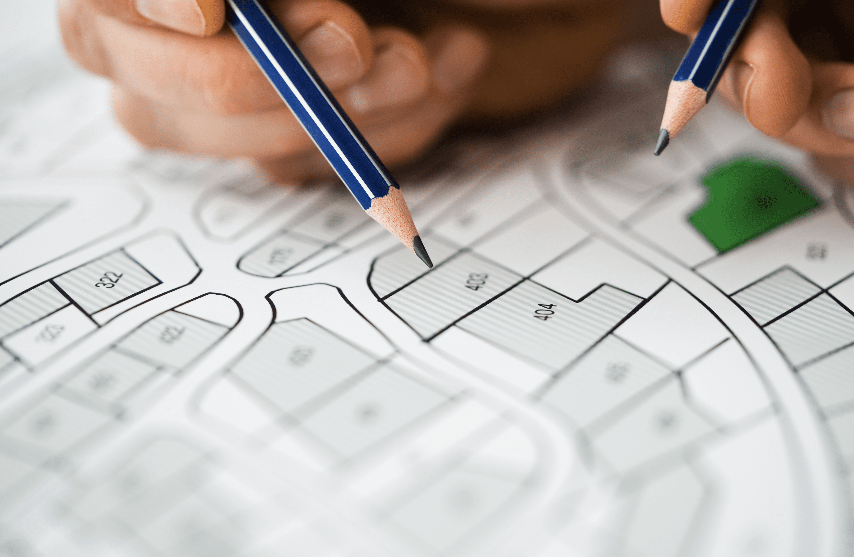 Stone Haven Developments Hands holding pencils over a site plan or architectural map for Stone Haven Developments, marking specific plots labeled with numbers, with one green highlighted area. Ontario