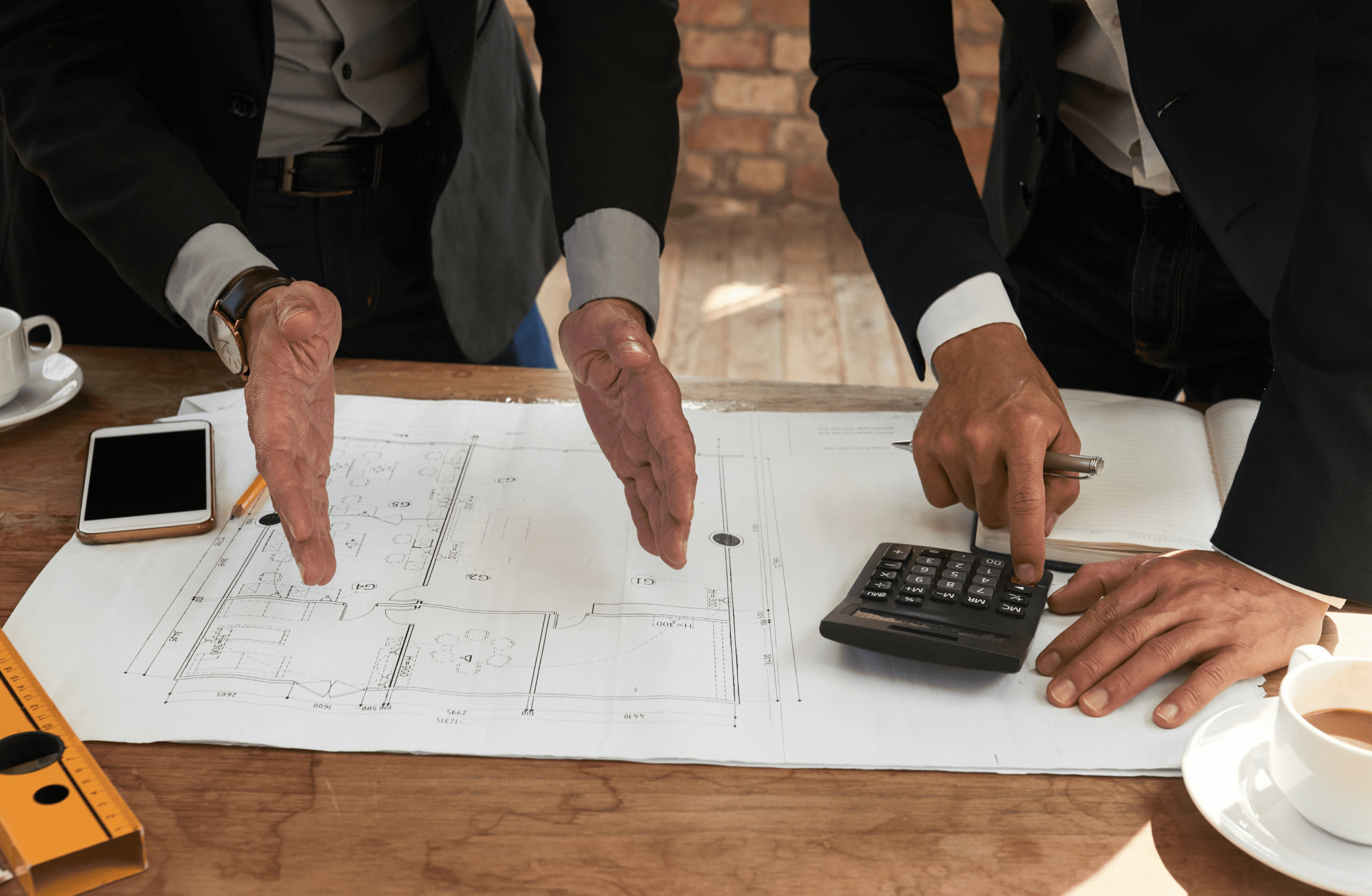 Stone Haven Developments Two people in business attire discuss architectural blueprints for Stone Haven Developments, with one using a calculator and the other gesturing toward the plans on the table. Ontario