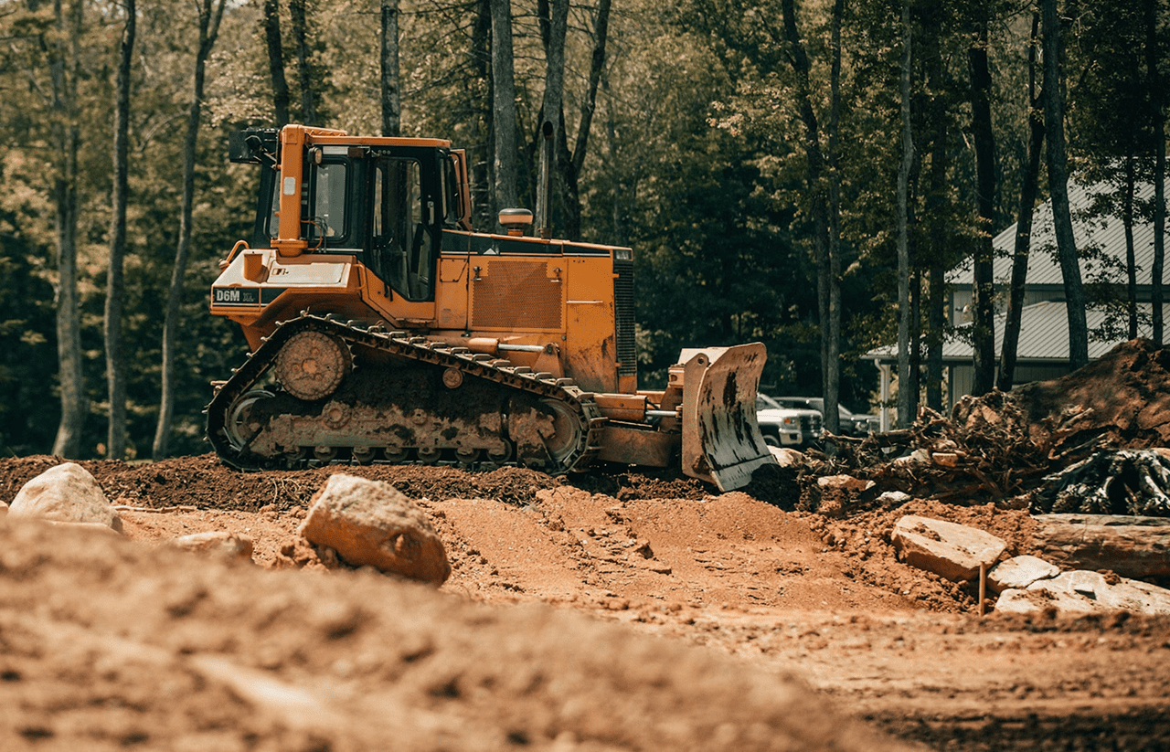 Stone Haven Developments A yellow bulldozer pushes dirt and debris on a construction site surrounded by trees. Ontario