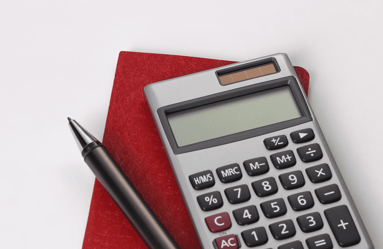 Stone Haven Developments A calculator, a closed red notebook, and a black pen are arranged on a white surface. Ontario