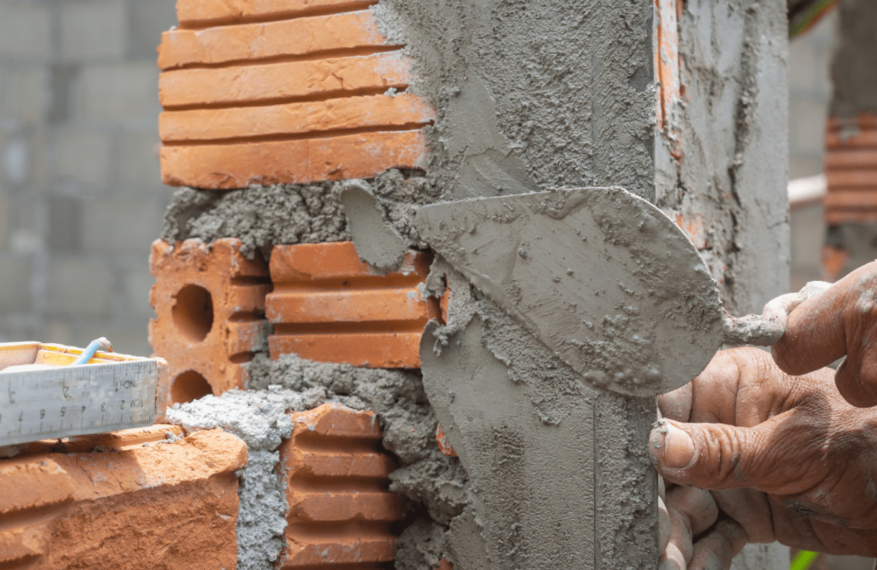 Stone Haven Developments A close-up of a person applying mortar to brickwork with a trowel during wall construction. Ontario