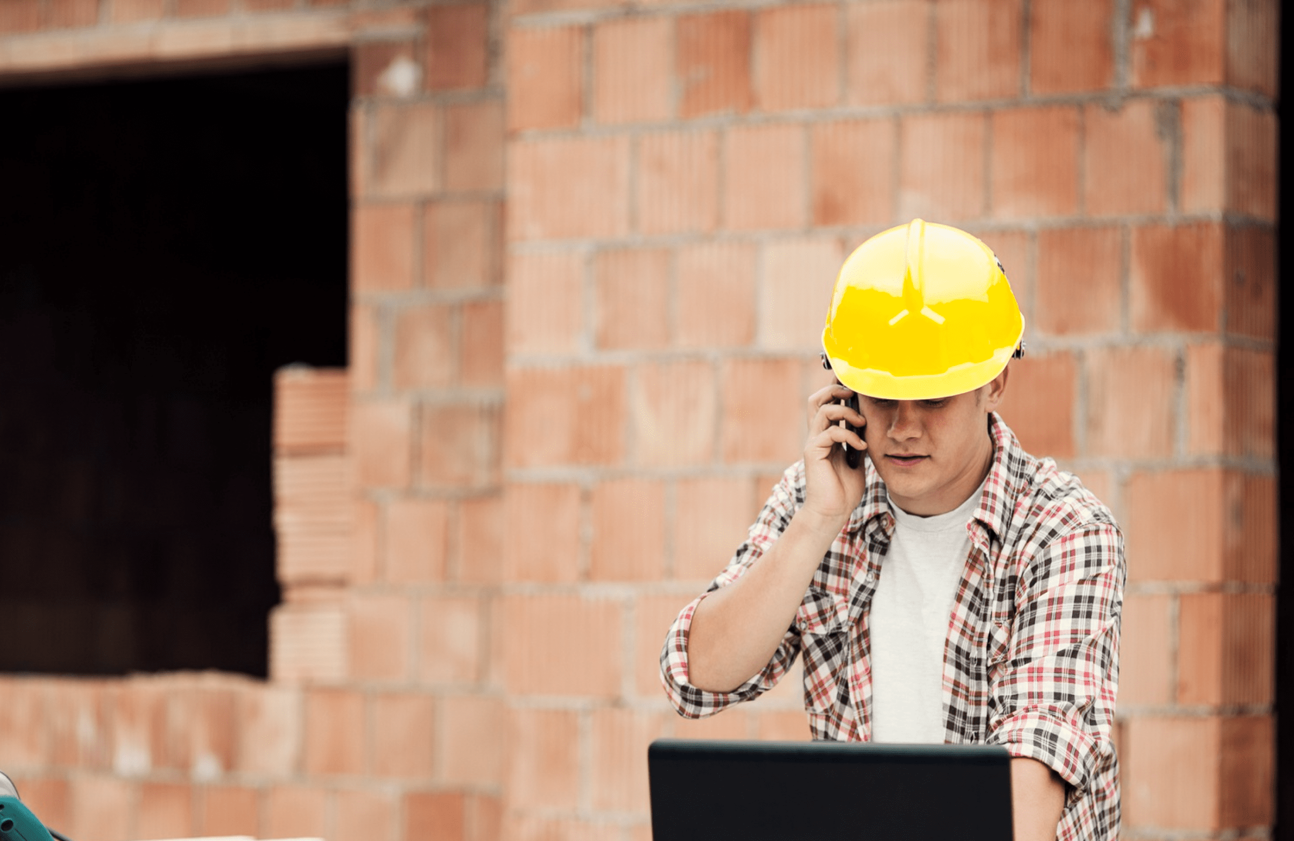Construction workers in safety gear reviewing a project outdoors near building materials.
