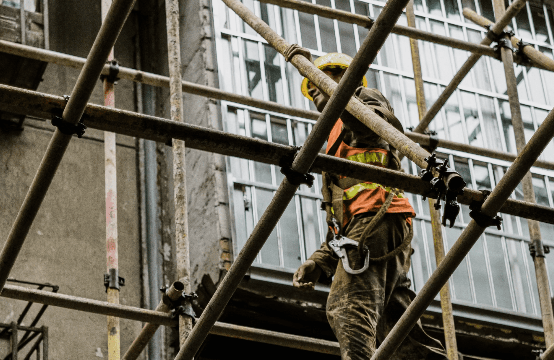 Stone Haven Developments A construction worker wearing a helmet and safety gear stands on metal scaffolding in front of a building with large windows. Ontario