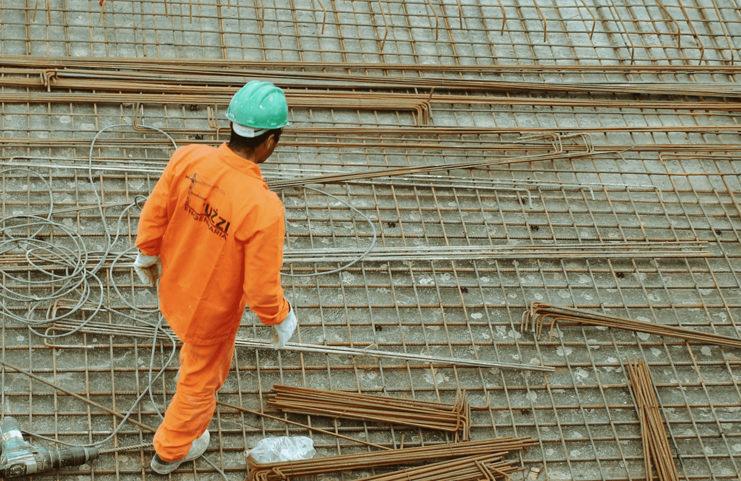 Stone Haven Developments A construction worker in an orange uniform and green helmet walks on a rebar grid at a building site. Ontario