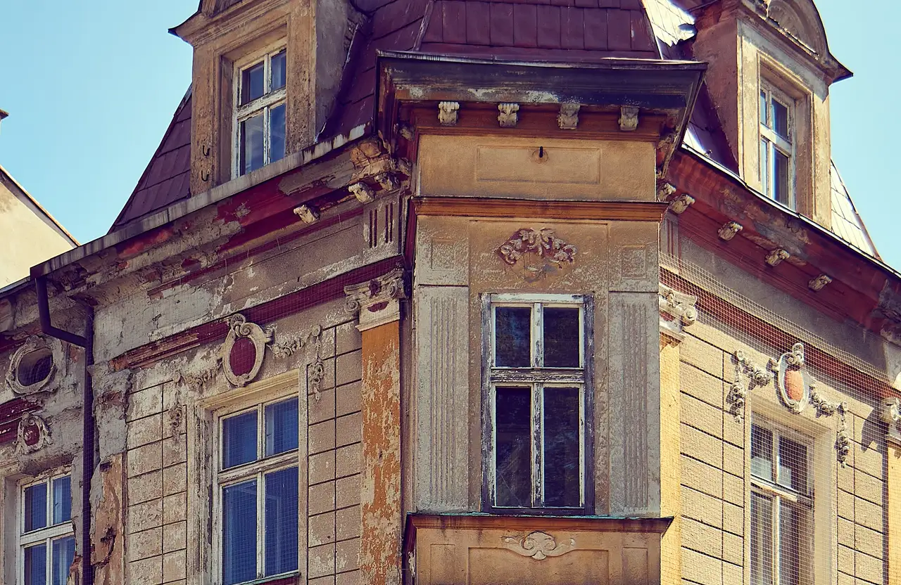 Stone Haven Developments Close-up of an old building facade with peeling paint, decorative moldings, and several windows showing signs of weathering and age. Ontario