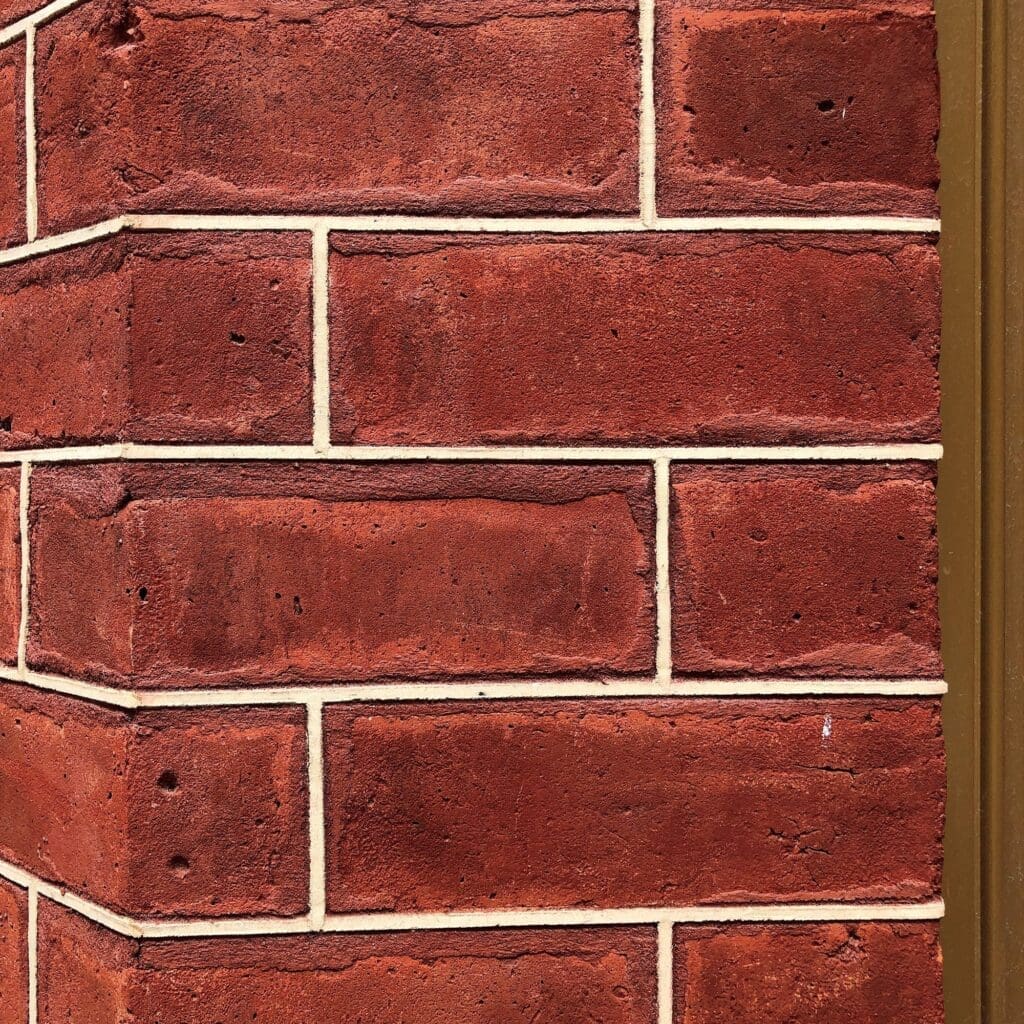 Stone Haven Developments Close-up view of a red brick wall corner with beige mortar and a vertical brown trim on the right side. Ontario