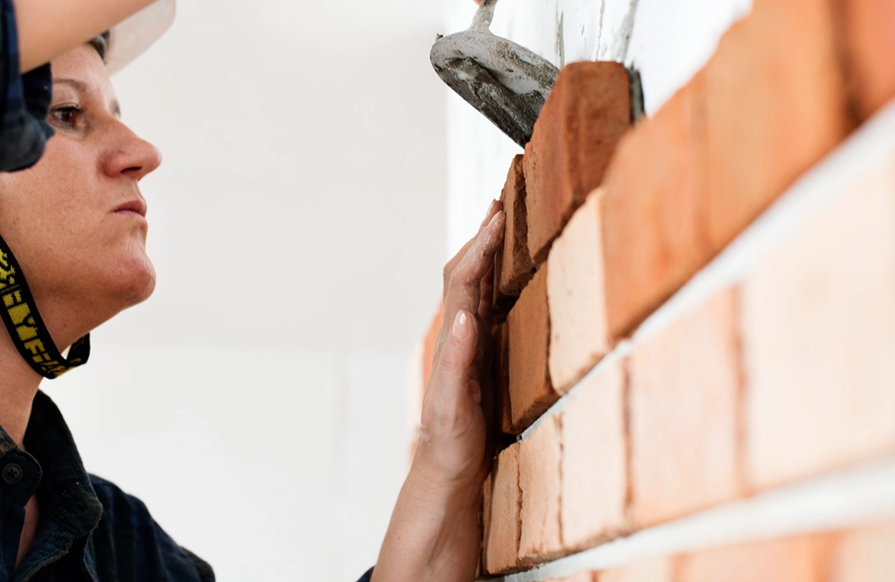 Stone Haven Developments Person laying red bricks on a wall, smoothing mortar with a trowel. Ontario