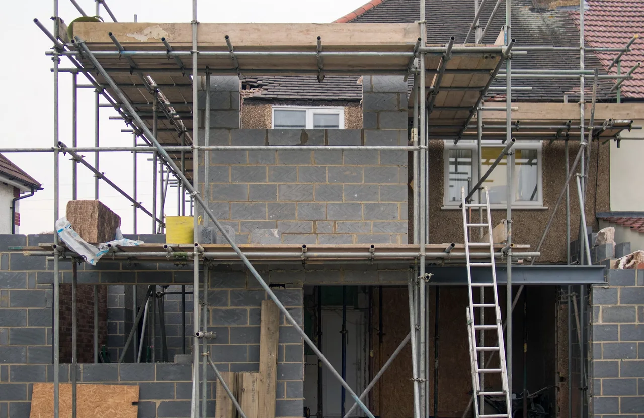 Stone Haven Developments A partially constructed house extension with scaffolding, bricks, and a ladder in front of an existing house. Ontario