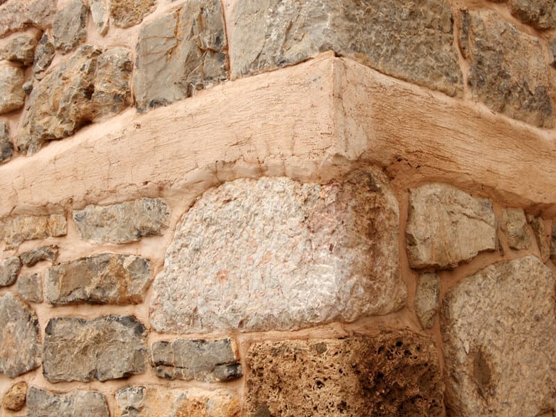 Stone Haven Developments Close-up view of the corner of a stone wall crafted by Stone Haven Developments, showing large and small stones held together with beige mortar. Ontario