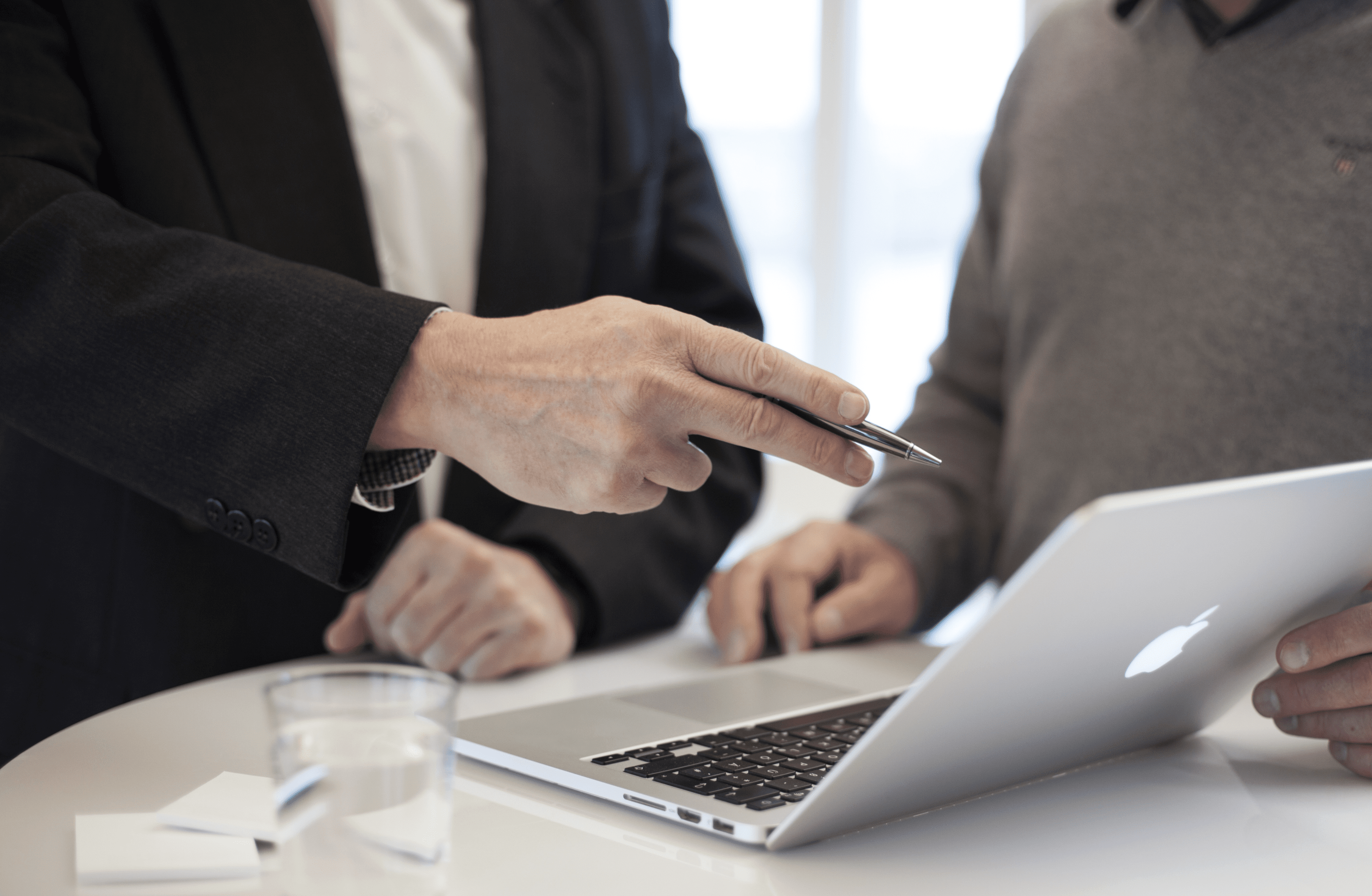 Stone Haven Developments Two people stand at a table with a laptop. One person in a suit from Stone Haven Developments gestures toward the screen with a pen, while a glass of water sits nearby. Ontario